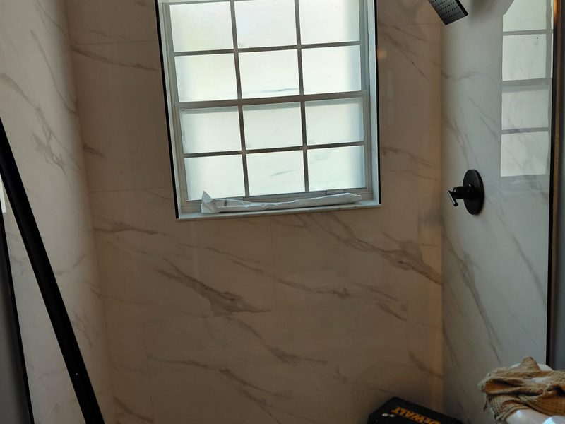 Marble-look tile shower with black fixtures